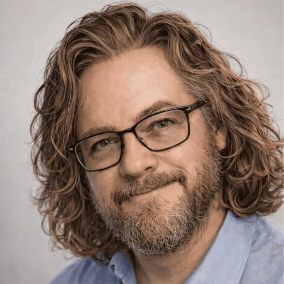 Chad Thiele, smiling, with long curly hair and glasses